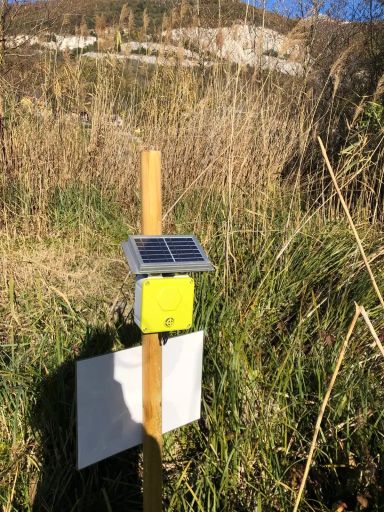 A solar-powered sensor on a post among dry grasses in Parco della Valle del Lambro